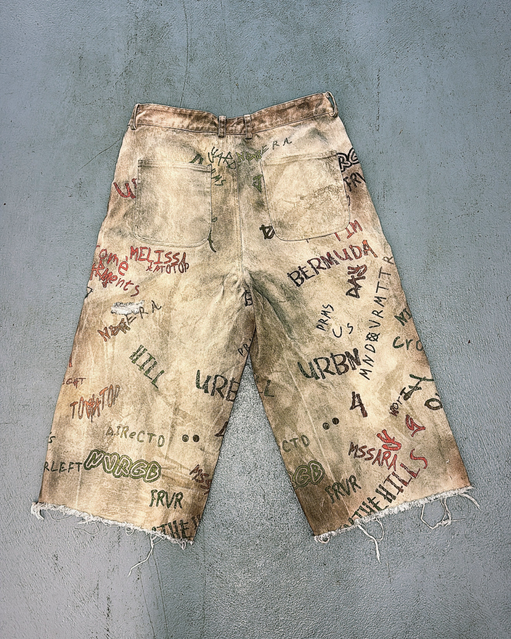 Worn shorts with graffiti-style text on a gray background